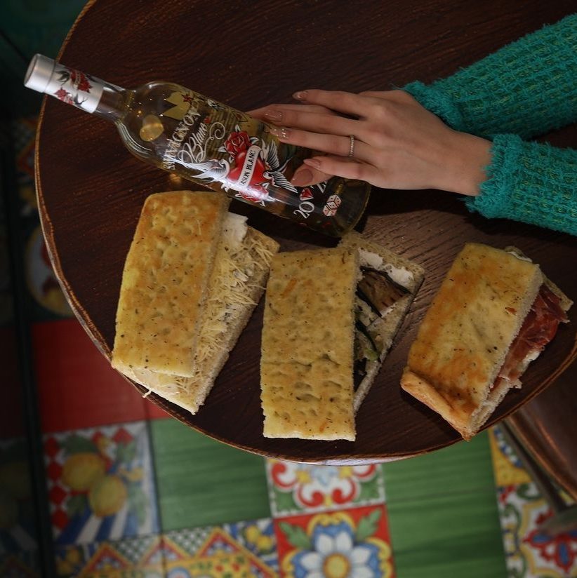 focaccia mise en avant sur une table avec une bouteille de vin blanc